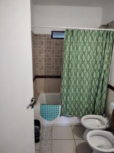 y baño con aseo y cortina de ducha. en Cómoda casa en El Volcan en San Luis