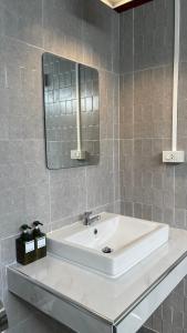 La salle de bains est pourvue d'un lavabo blanc et d'un miroir. dans l'établissement THA PAE SUNG - ท่าแพซุง, à Uthai Thani