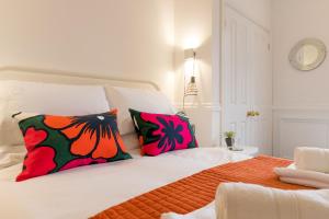 una camera da letto con un grande letto con cuscini colorati di All Saints Green Cottage - Norfolk Holiday Properties a Norwich