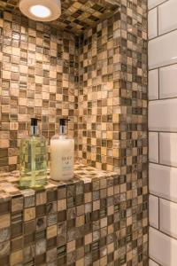 two bottles ofodorizers sit on a tiled bathroom at All Saints Green Cottage - Norfolk Holiday Properties in Norwich