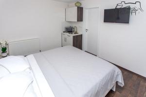 a bedroom with two white beds and a kitchen at Villa Ostrovica in Bihać