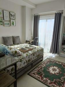 a bedroom with a bed and a window and a rug at Hola! Condotel @ Inspiria Davao in Davao City