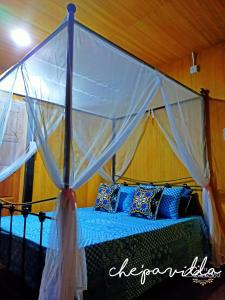 a bedroom with a canopy bed with blue pillows at Villa Mak Intan, Che'Pa Village Langkawi in Kuah