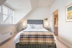 a bedroom with a large bed with two windows at Spectacular Penthouse , 100 yds to Old Course , Balcony in St Andrews
