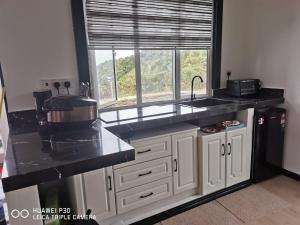 a kitchen with white cabinets and a sink and a window at Hounon White Chimney Cottage-4 Bedrooms in Ranau