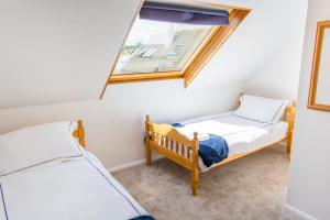 two twin beds in a room with a window at Quayside Cottage - Norfolk Holiday Properties in Wroxham