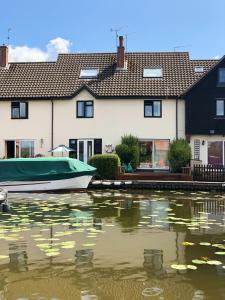 a boat in the water in front of houses at Quayside Cottage - Norfolk Holiday Properties in Wroxham