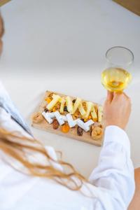 una persona che tiene in mano un bicchiere di vino e un piatto di cibo di HOM54 Luxury Suites a Heraklion