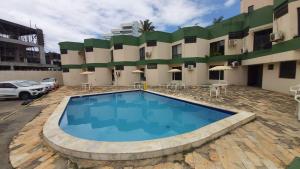 a hotel with a large swimming pool in front of a building at Apartamento Vilage na Praia de Armação Salvador in Salvador