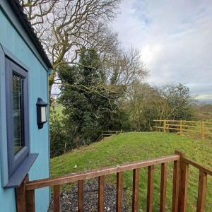 a blue house with a wooden railing and a field at The Shepherd's Delight in Rushton Spencer