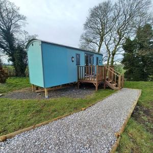 a blue tiny house sitting on top of a field at The Shepherd's Delight in Rushton Spencer