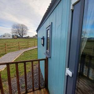 una casa azul con una puerta y una valla en The Shepherd's Delight, en Rushton Spencer