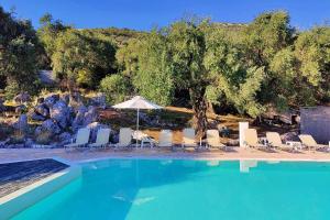 a group of chairs and an umbrella next to a swimming pool at Nissaki Sea View 203 by Sealand Villas in Nisakion