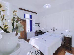 a white room with a bed and a vase with flowers at Anticlea I in Vathi