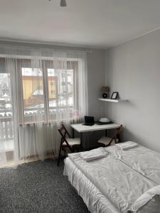 a bedroom with a bed and a desk and a window at Willa Ewa in Krynica Zdrój