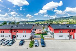 a row of red buildings with cars parked in a parking lot at KORZO LIPNO 2 in Lipno nad Vltavou