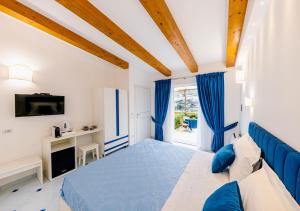 1 dormitorio grande con 1 cama azul y TV en La Margherita Fiorita, en Ravello