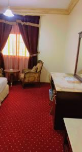 une chambre d'hôtel avec un lit, une chaise et un tapis rouge dans l'établissement فندق كراون نجران, à Najran