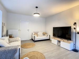 uma sala de estar com uma televisão de ecrã plano e um sofá em Vakantiewoning De Gavers em Geraardsbergen