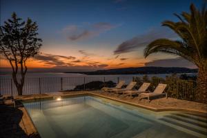 uma piscina com espreguiçadeiras e um pôr-do-sol em 360ᵒ Residences em Khelmáta