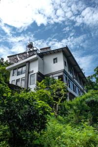 un edificio blanco con árboles delante de él en Haut Monde Hill Stream Resort and Spa, en Dehradun