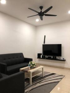 MOFA Homestay Near KLIA Airport في سيبانغ: غرفة معيشة مع أريكة سوداء وتلفزيون بشاشة مسطحة