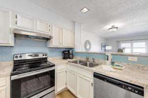a kitchen with white cabinets and a stove and a sink at Bammers Beach Spot OS26 in Corolla