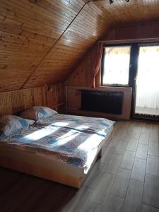 a bed in a wooden room with two windows at Málnás Szállás in Dunavarsány