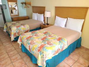 a hotel room with two beds and a mirror at Parador Maunacaribe - Maunabo in Maunabo