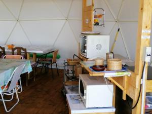 una habitación con microondas y mesas en una yurta en Agriturismo Glamping Erbe Matte en SantʼAntìoco