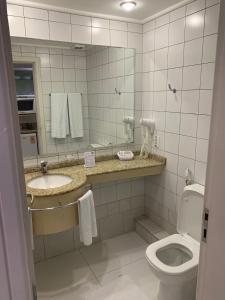 a bathroom with a toilet and a sink and a mirror at Studio no Jurerê Beach Village - Pé na areia in Florianópolis +12 photos