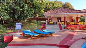 eine Gruppe von Stühlen und einem Sonnenschirm auf einer Terrasse in der Unterkunft Lemon Creek Hotel Resort in Bijilo