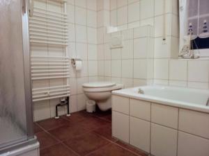 La salle de bains blanche est pourvue de toilettes et d'une baignoire. dans l'établissement Drei-Insel-Blick Neßmersiel, à Nessmersiel