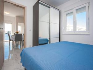 a bedroom with a blue bed and a table at Apartments Happy Holiday in Rogoznica