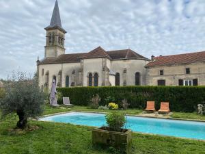 una iglesia con una torre del reloj y una piscina en LE CHATEAU DE MONTHUREUX LE SEC, en Monthureux-le-Sec