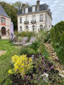 a house with two chairs in a garden with flowers at LE CHATEAU DE MONTHUREUX LE SEC in Monthureux-le-Sec