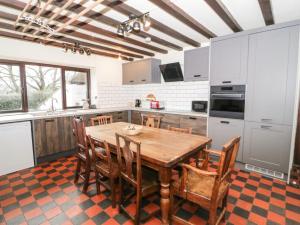 a kitchen with a wooden table and some chairs at Cymryd Uchaf in Conwy