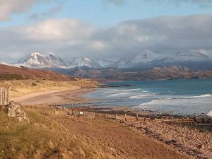 a beach with snow covered mountains in the background at Otters Retreat in Big Sand