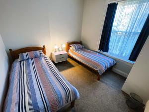 2 camas en una habitación pequeña con ventana en Orchard Cottage, en Ventnor