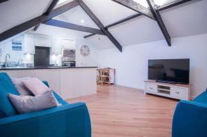 a living room with a blue couch and a kitchen at The Penthouse At The Mews - 2 Bedroom Apartment - Tenby in Tenby
