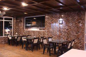 a restaurant with tables and chairs against a stone wall at GOLDEN GREEN in Munnar