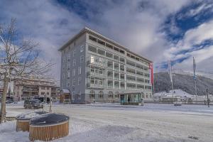 ein großes Gebäude im Schnee neben einer Straße in der Unterkunft ALPINE INN Davos in Davos