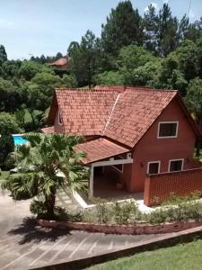 uma casa vermelha com um telhado vermelho e uma palmeira em Alugo linda casa de campo perto de São Paulo com ótimo jardim, piscina e lareira. em Sará-Sará