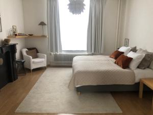 een slaapkamer met een bed, een stoel en een raam bij B&B Alexander in Maastricht