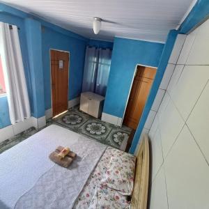 um pequeno quarto com uma cama e paredes azuis em Hospedaria Oliveira em São Tomé das Letras