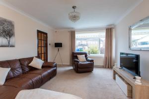 a living room with a brown leather couch and a television at Mitford Close in Shincliffe