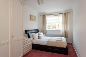 a bedroom with a bed with a dresser and a window at Mitford Close in Shincliffe