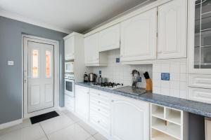 a white kitchen with white cabinets and appliances at Mitford Close in Shincliffe