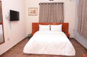 um quarto com uma cama branca e uma televisão em House 5 Ibara Housing, Abeokuta em Abeokuta