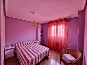 purpurowa sypialnia z łóżkiem i oknem w obiekcie Apartamento Montse Zaragoza w Saragossie